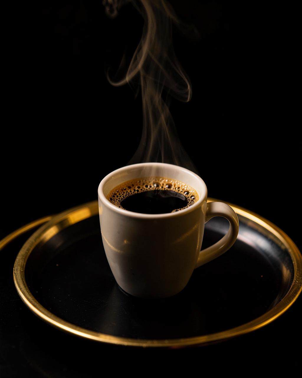 Een kop pure zwarte koffie op een dienblad met gouden rand